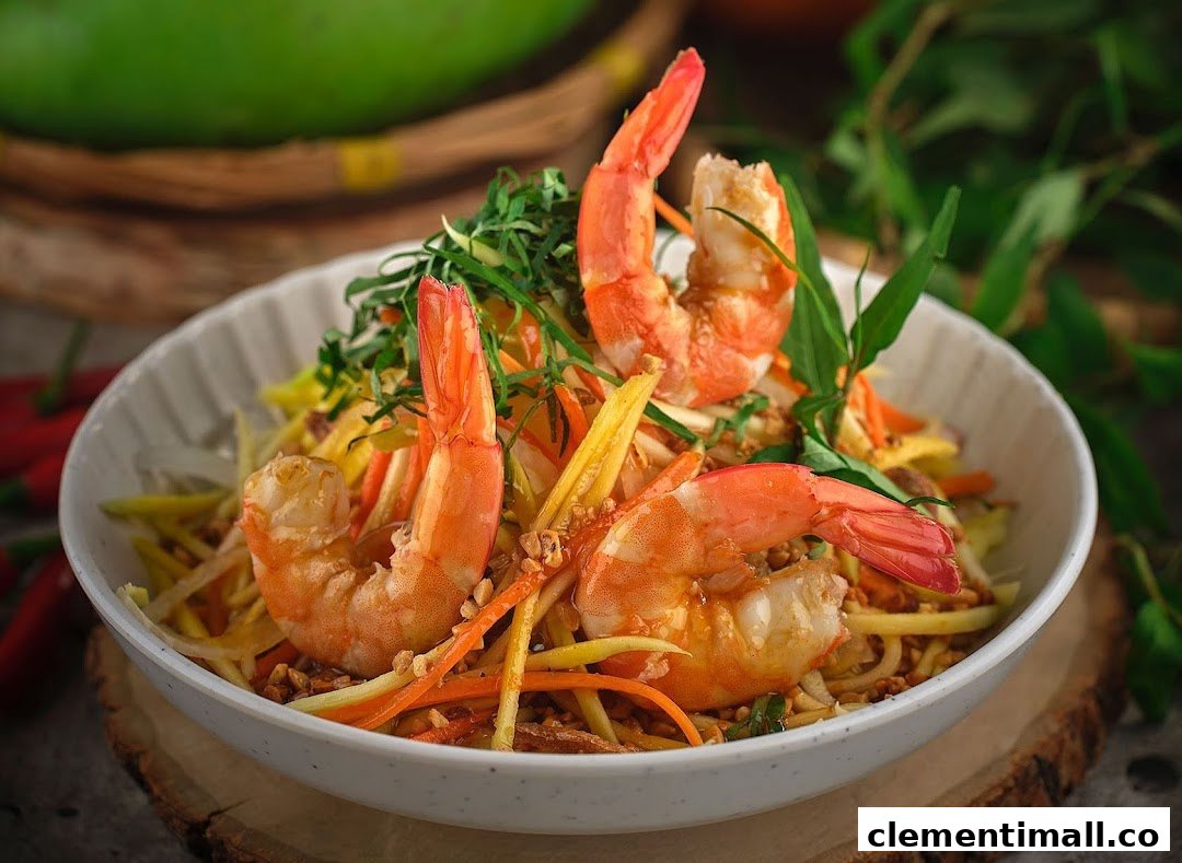 A vibrant Vietnamese salad featuring fresh shrimp, shredded mango, and herbs in a white bowl.