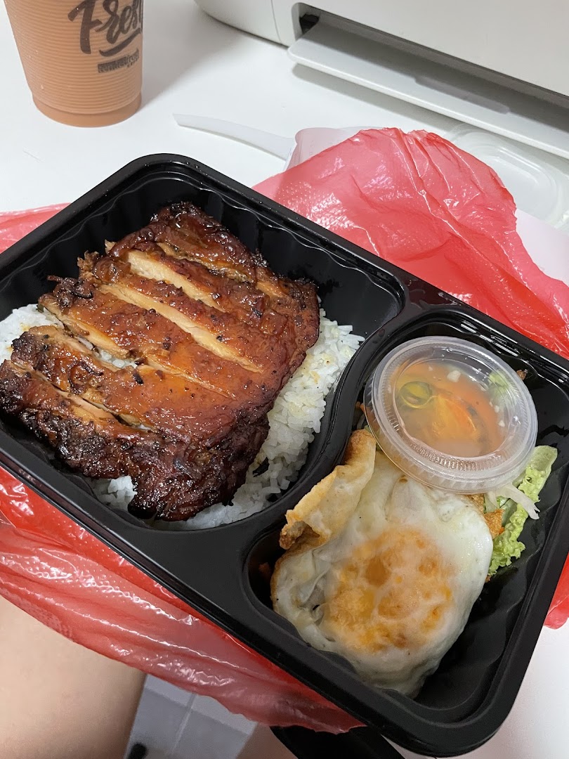 A delicious takeaway meal featuring grilled chicken, rice, fried egg, and a side sauce.