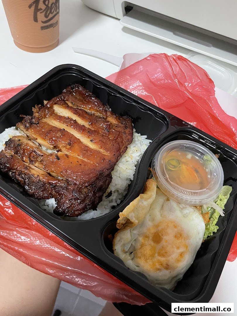 A delicious takeaway meal featuring grilled chicken, rice, fried egg, and a side sauce.