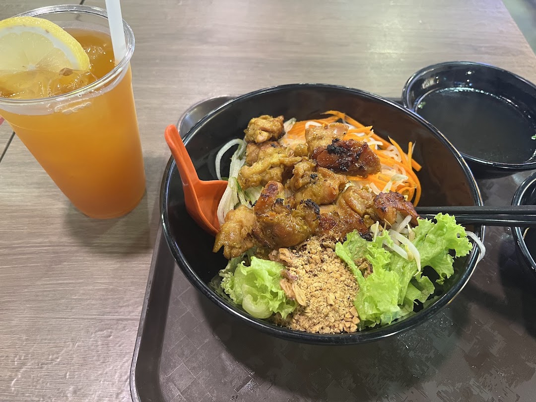 A delicious bowl of Vietnamese grilled chicken noodles with fresh vegetables and a refreshing iced tea.