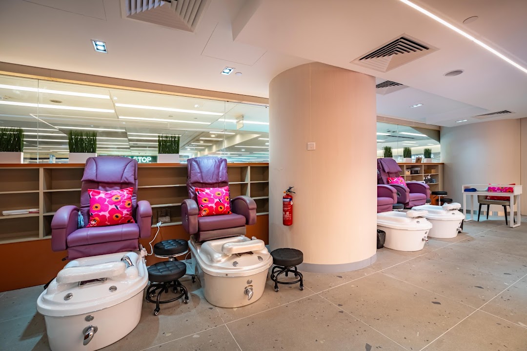 Interior view of a nail spa featuring comfortable purple pedicure chairs and foot baths.