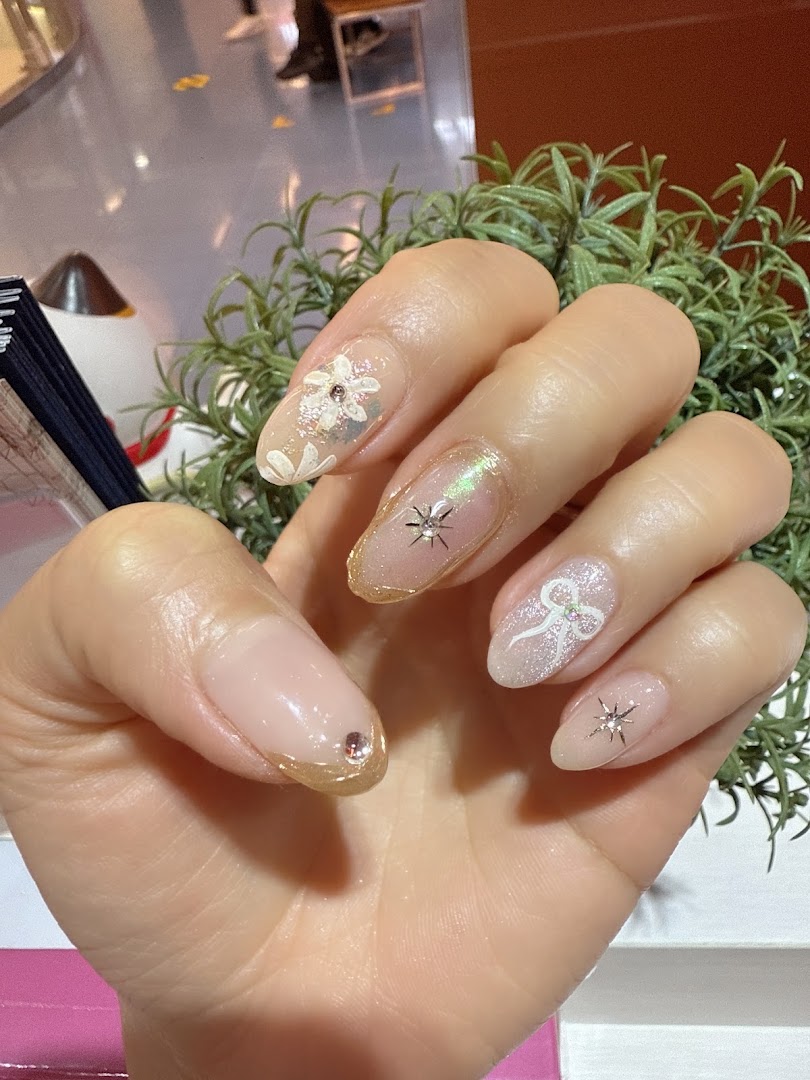 A hand showcasing beautifully manicured nails with intricate designs, glitter, and embellishments.