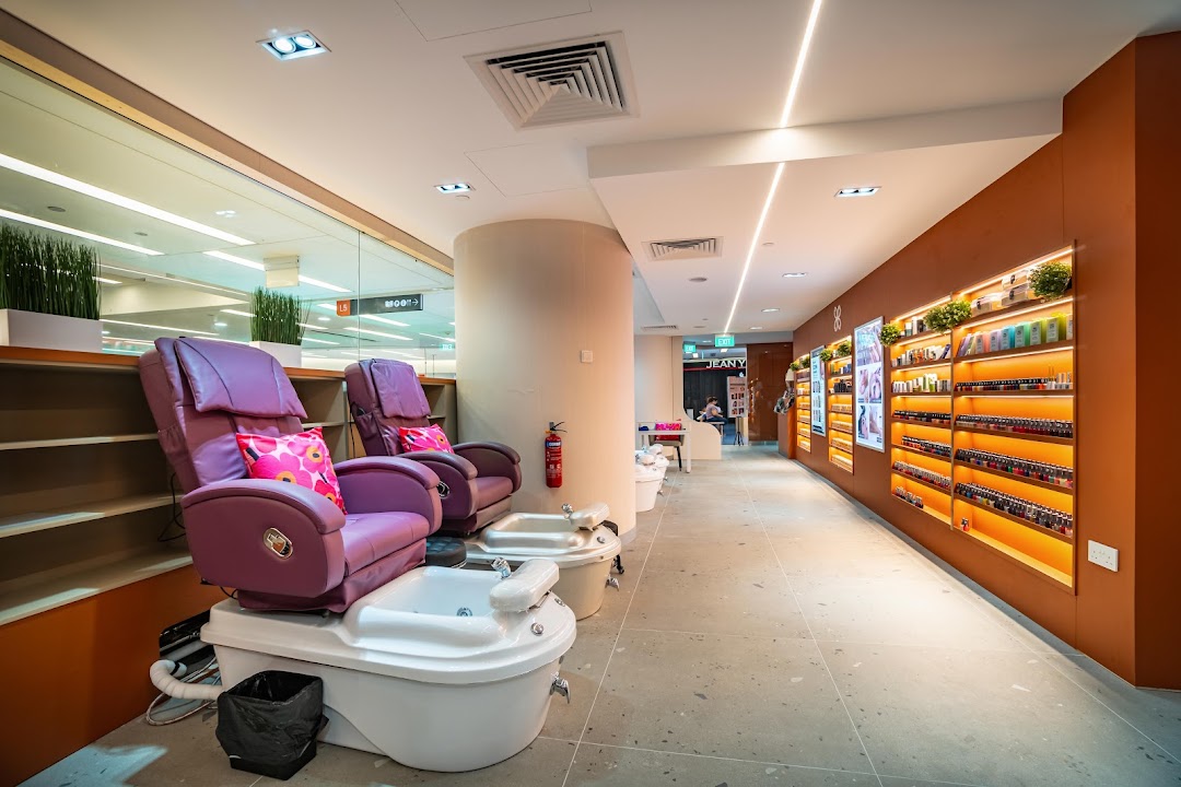 Interior view of Pixie Nail Spa featuring comfortable purple pedicure chairs and illuminated nail polish displays.
