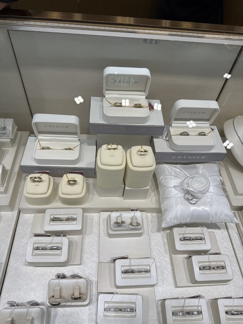 A display case showcasing various rings, necklaces, and a white wedding ring pillow.