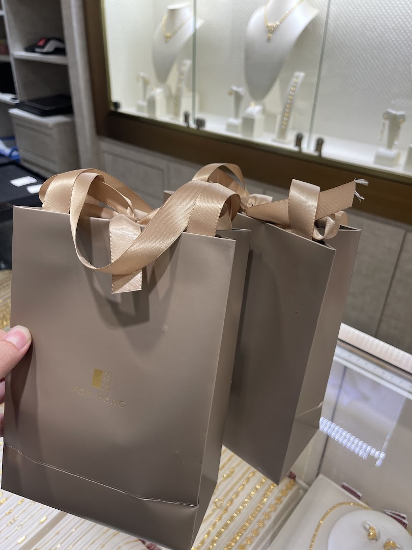 Two Poh Heng shopping bags with gold jewellery displays visible in the background.