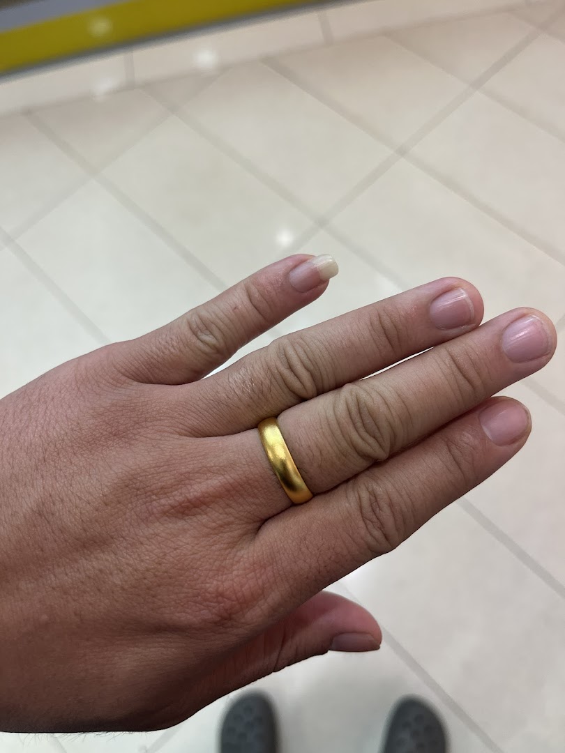 A hand showcasing a simple, elegant gold ring, likely a product from the jewellery shop.