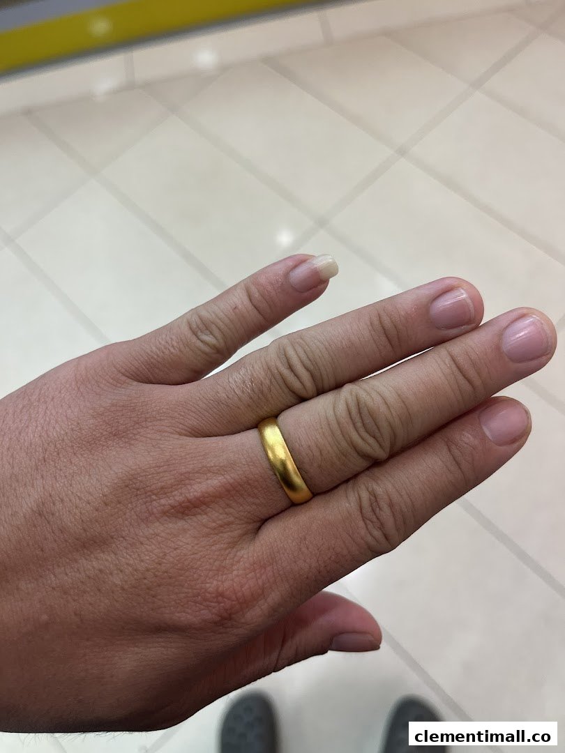A hand showcasing a simple, elegant gold ring, likely a product from the jewellery shop.