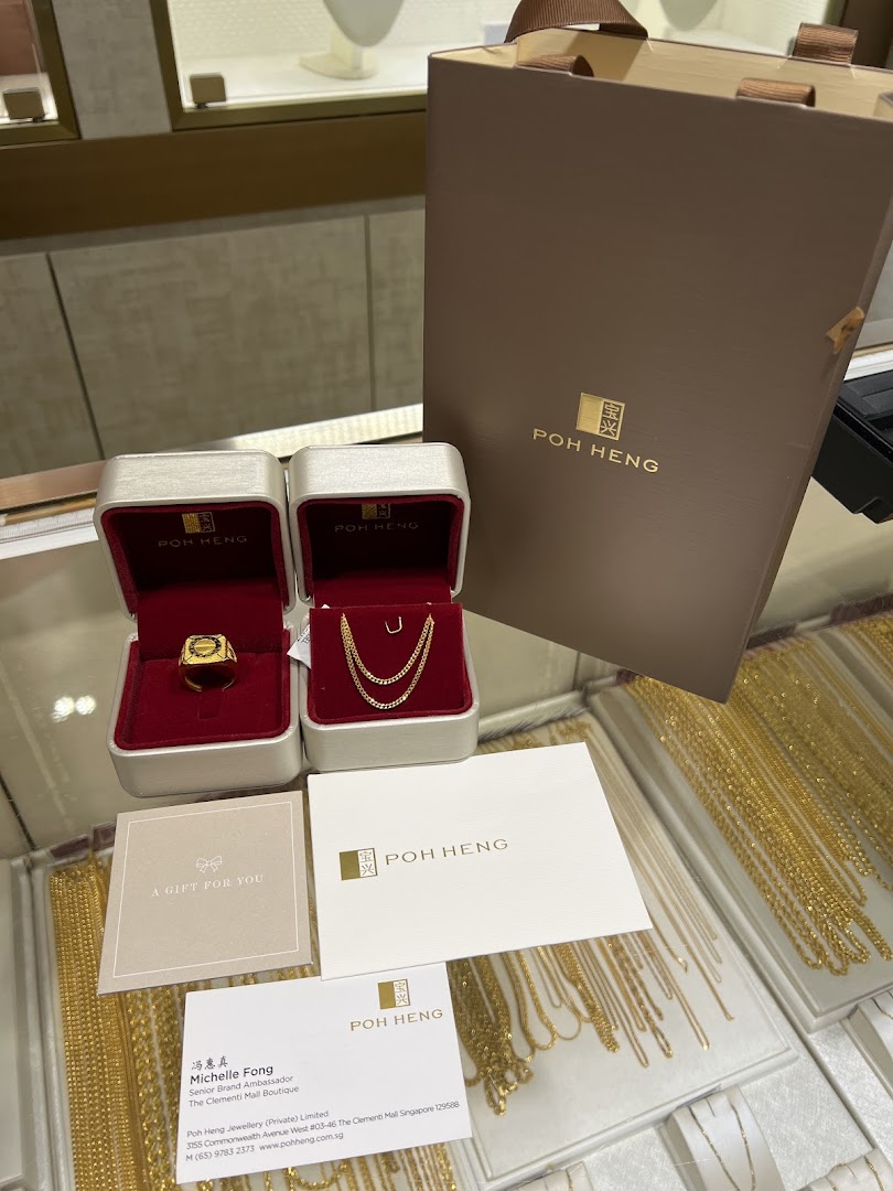 Gold jewelry in gift boxes with Poh Heng packaging and a business card on display.
