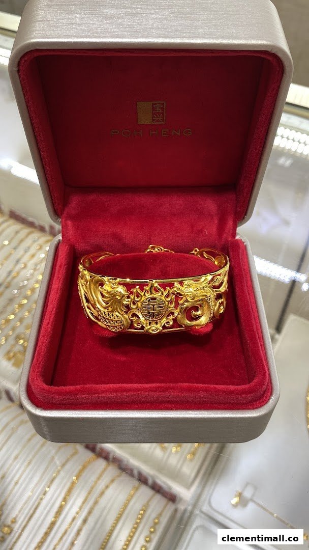 A stunning gold bracelet with intricate dragon and phoenix design displayed in a red Poh Heng Jewellery box.
