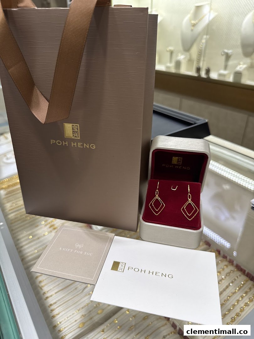 A pair of gold earrings in a box with Poh Heng packaging and a gift card.