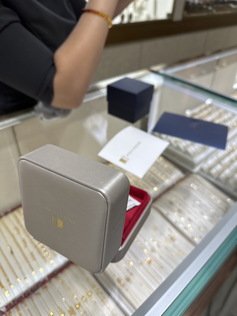 An open jewellery box on a display counter inside Poh Heng Jewellery, with a staff member in the background.