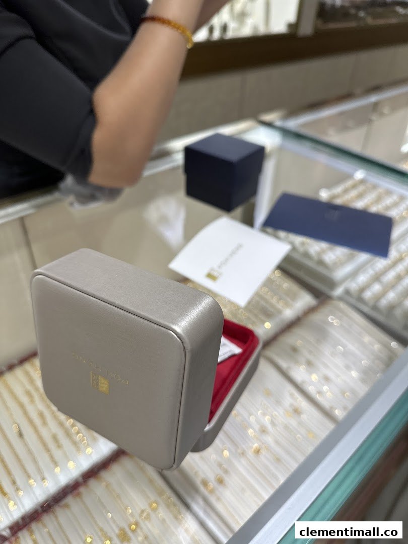 An open jewellery box on a display counter inside Poh Heng Jewellery, with a staff member in the background.