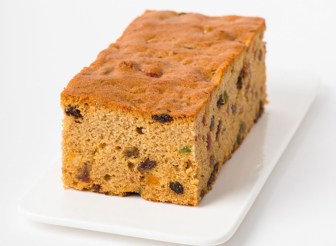A rectangular fruit cake with visible dried fruits on a white platter.