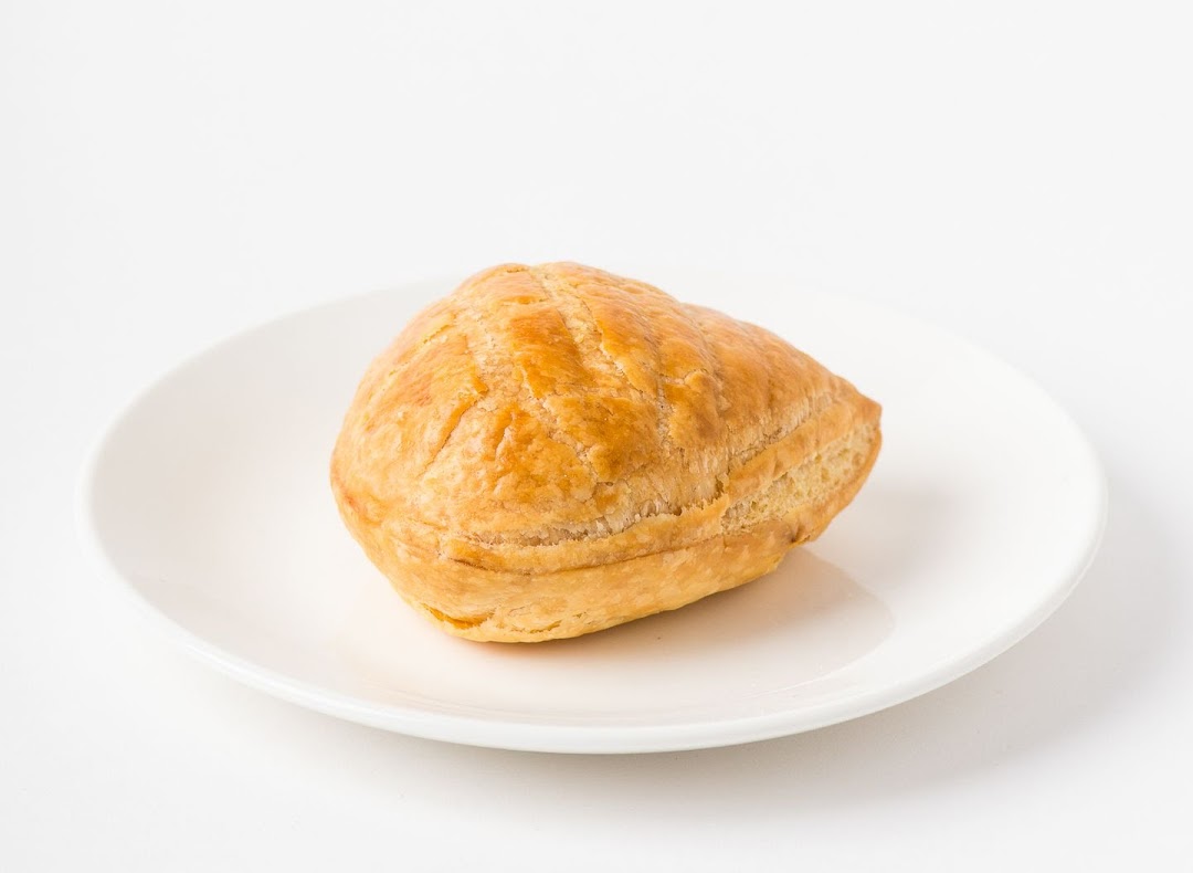 A golden-brown pastry, likely a puff or pie, rests on a white plate.