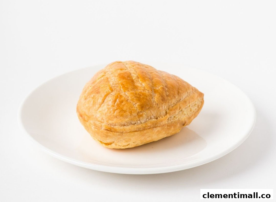 A golden-brown pastry, likely a puff or pie, rests on a white plate.