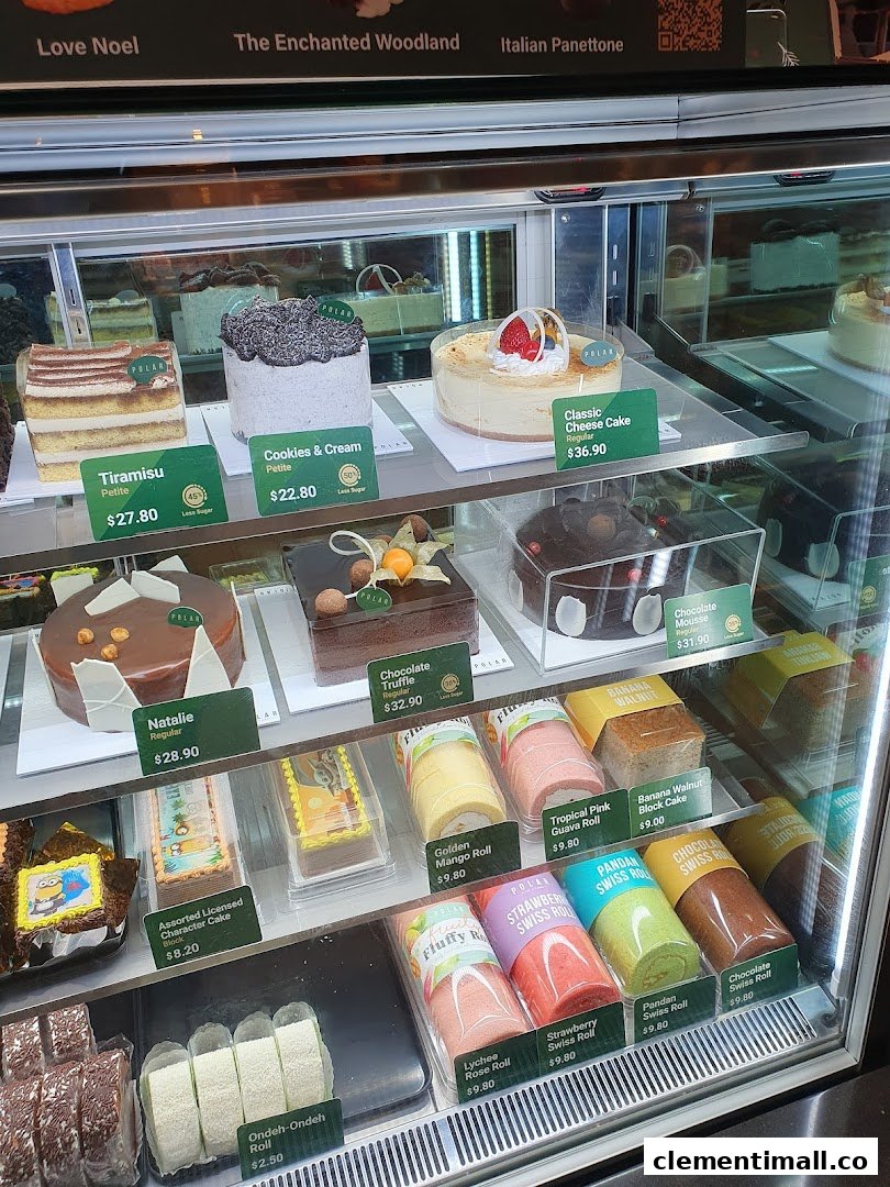 A vibrant display case showcasing a variety of cakes, swiss rolls, and pastries with prices.