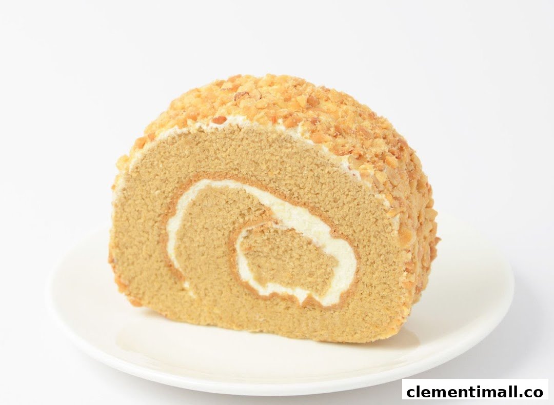 A delicious slice of nut-topped cake roll with cream filling on a white plate.