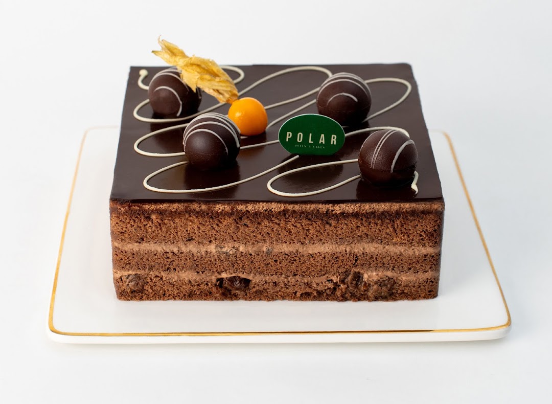 A decadent square chocolate cake with ganache, chocolate truffles, and a Polar Puffs & Cakes tag.