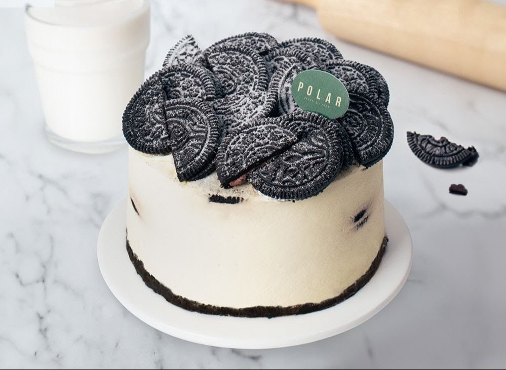 A delicious white cake topped with numerous Oreo cookies and powdered sugar.