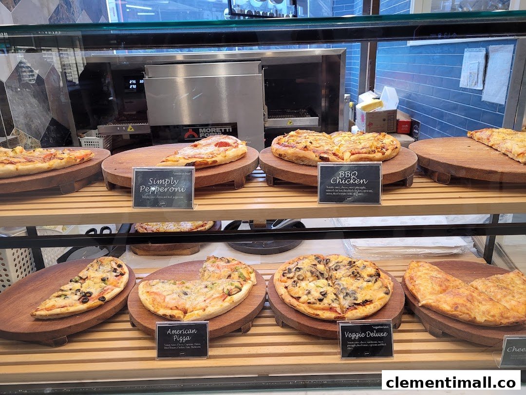 A display case filled with various freshly baked pizzas and savory items at Proofer Boulangerie.