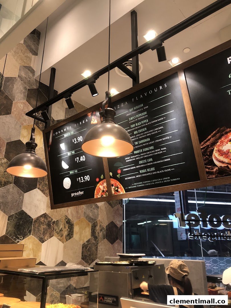 A menu board displaying pizza sizes and flavors, with a staff member preparing food.