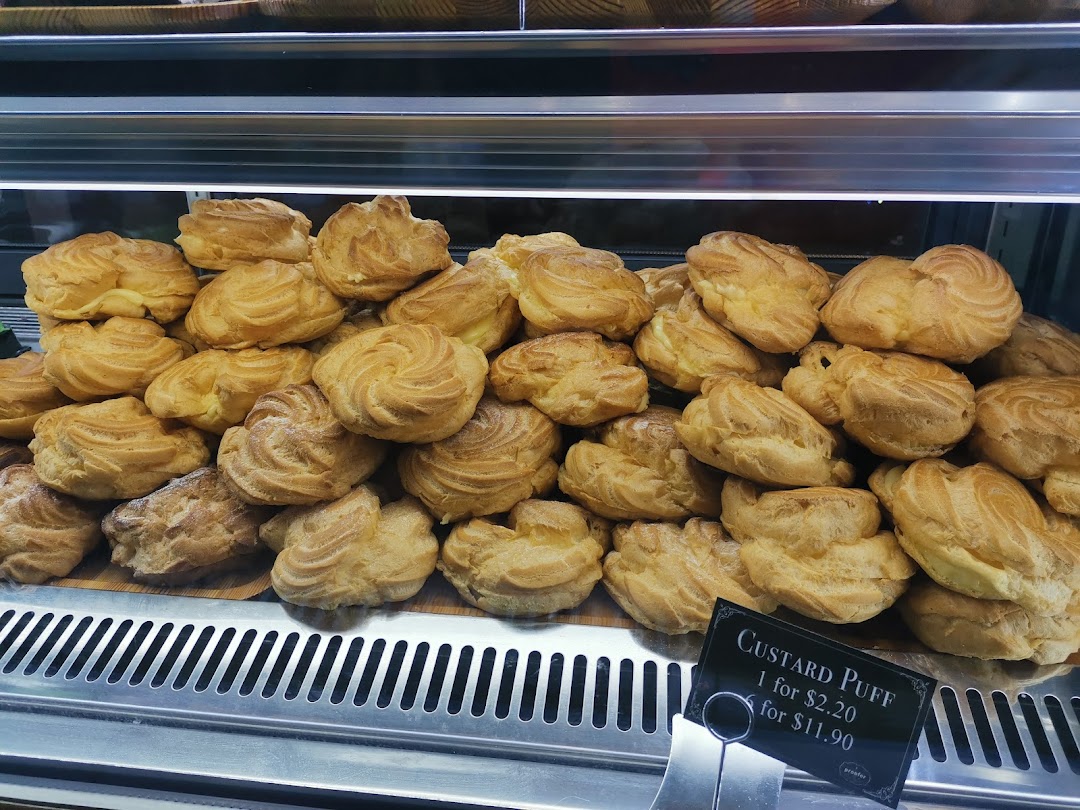 A display of golden-brown custard puffs in a bakery showcase, with a price tag visible.