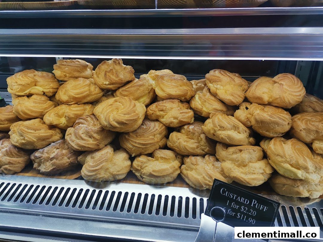 A display of golden-brown custard puffs in a bakery showcase, with a price tag visible.