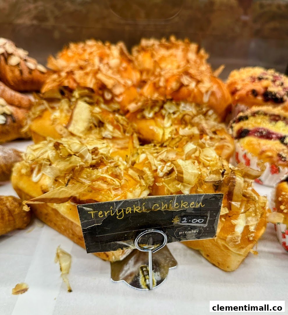 Close-up of freshly baked Teriyaki Chicken bread and other savory pastries in a bakery display.
