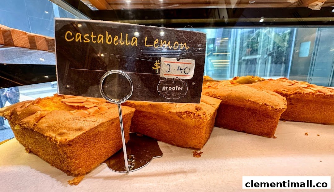 Close-up of freshly baked Castabella Lemon loaves displayed in a bakery showcase with a price tag.