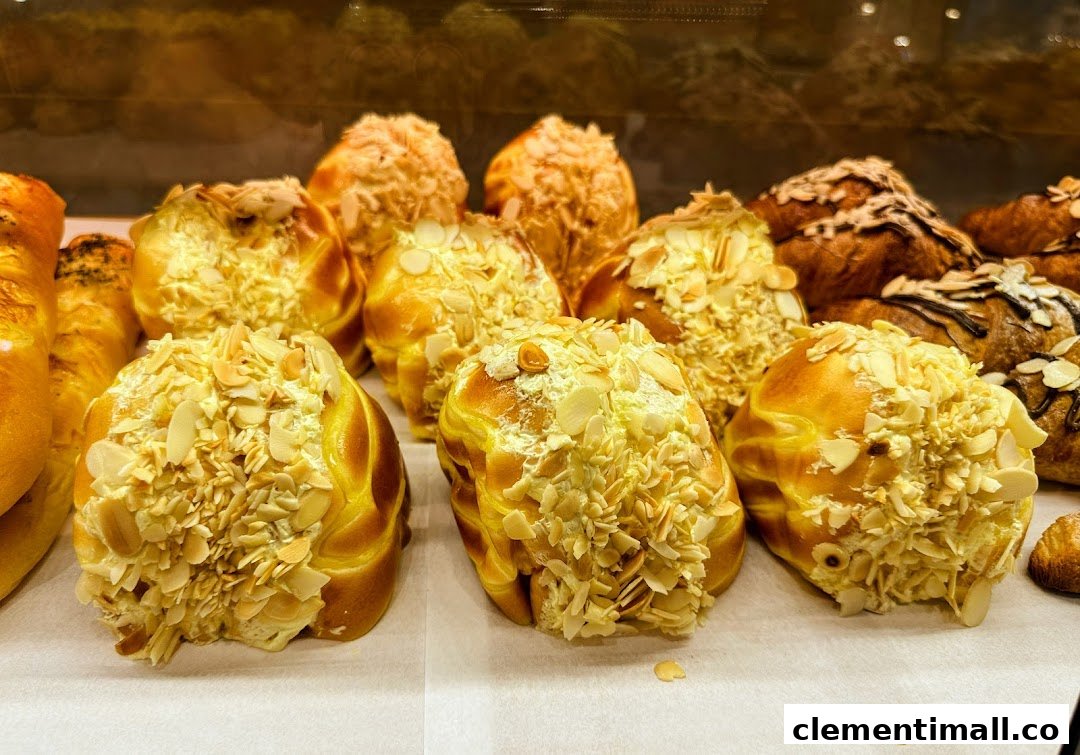 Close-up of golden-brown pastries topped with generous almond flakes in a bakery display.