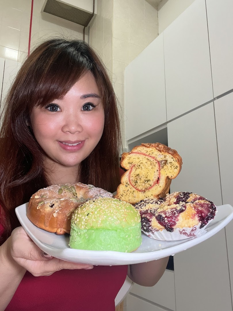A person smiling while holding a plate with various freshly baked breads and pastries from Proofer Boulangerie.