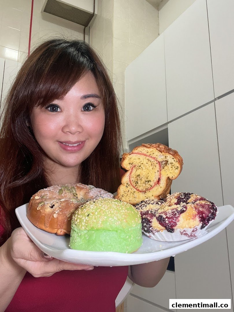 A person smiling while holding a plate with various freshly baked breads and pastries from Proofer Boulangerie.