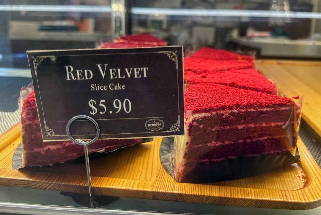 Close-up of Red Velvet Slice Cake with price tag displayed in a bakery showcase.