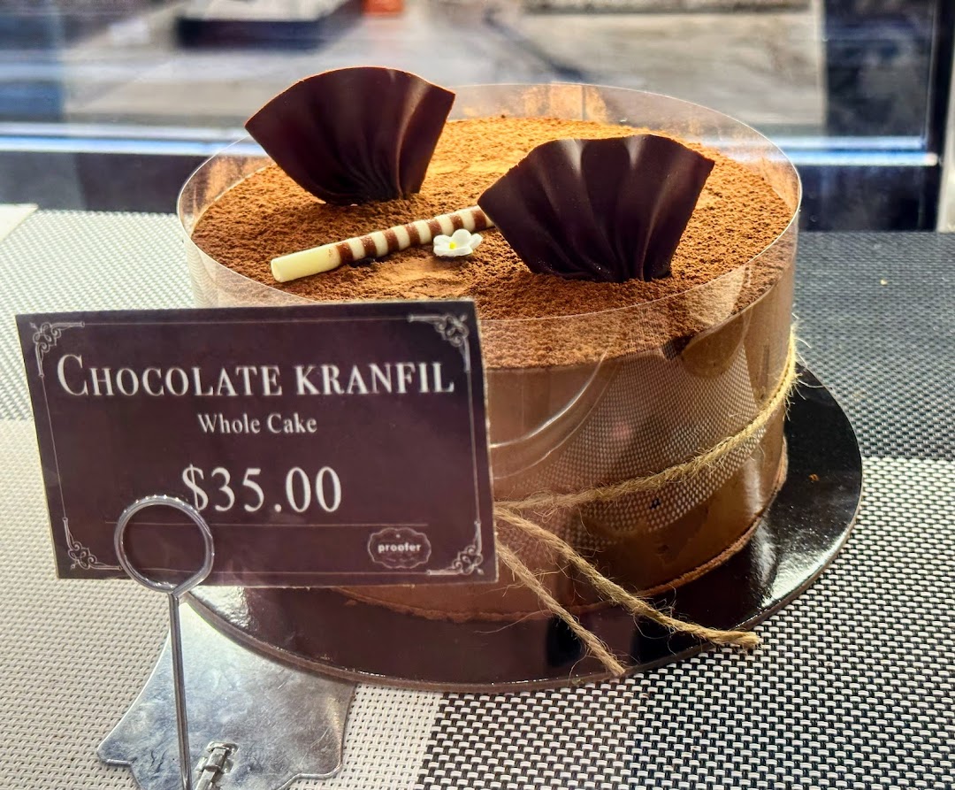A decadent Chocolate Kranfil whole cake with chocolate decorations and a price tag displayed.