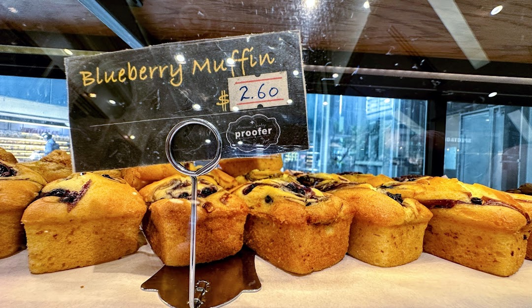 A close-up of freshly baked blueberry muffins with a price tag at Proofer Boulangerie.