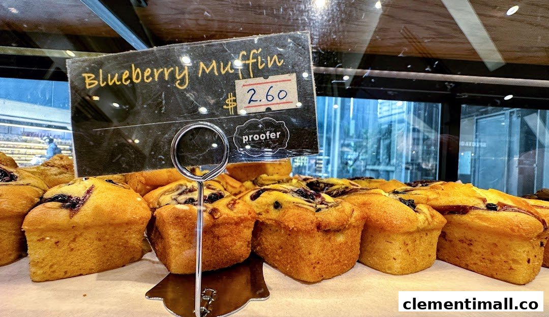 A close-up of freshly baked blueberry muffins with a price tag at Proofer Boulangerie.