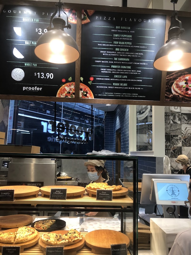 A vibrant display of fresh pizzas and a detailed menu board at Proofer Boulangerie.