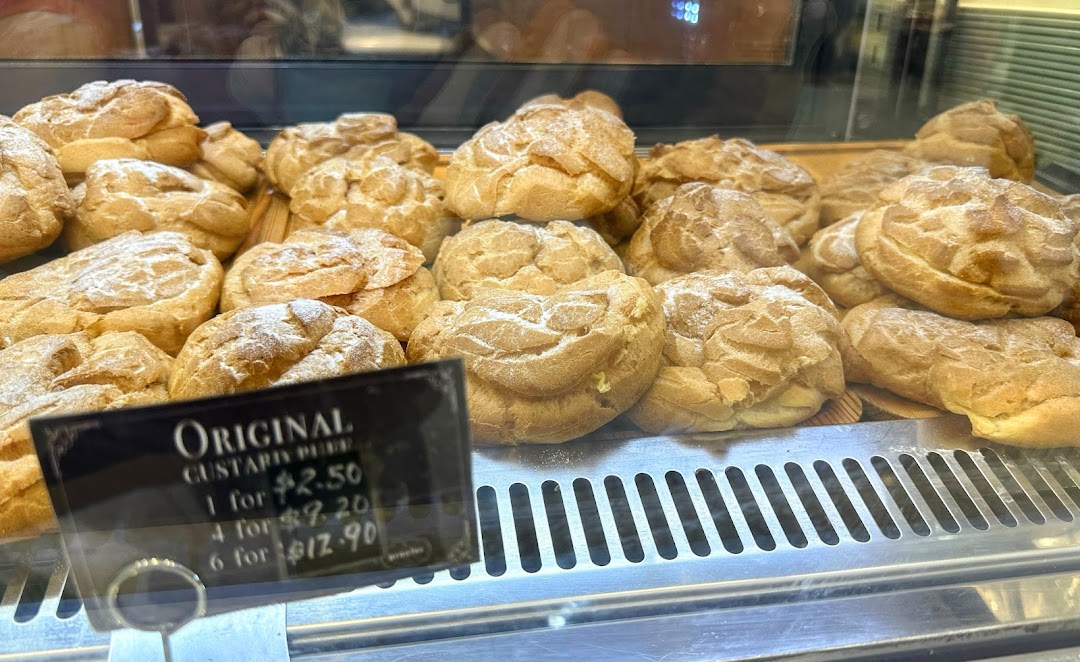 A display case filled with freshly baked Original Custard Puffs, showing their pricing.