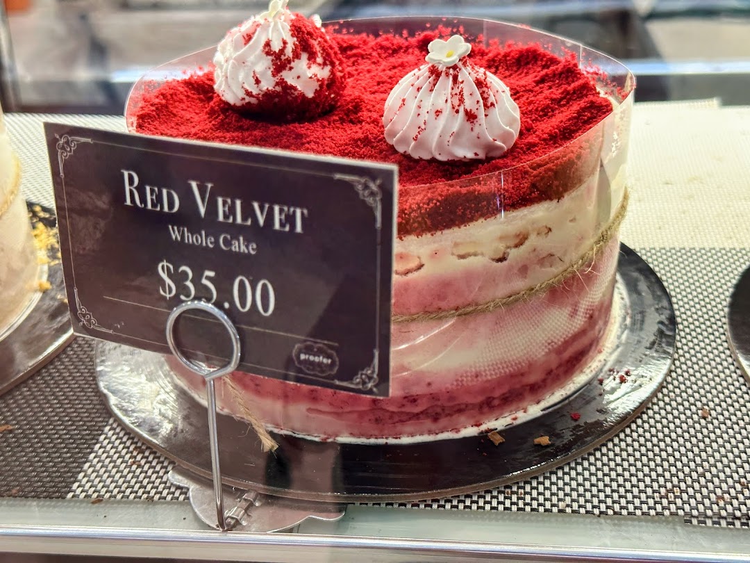 A vibrant Red Velvet whole cake with a price tag displayed in a bakery.