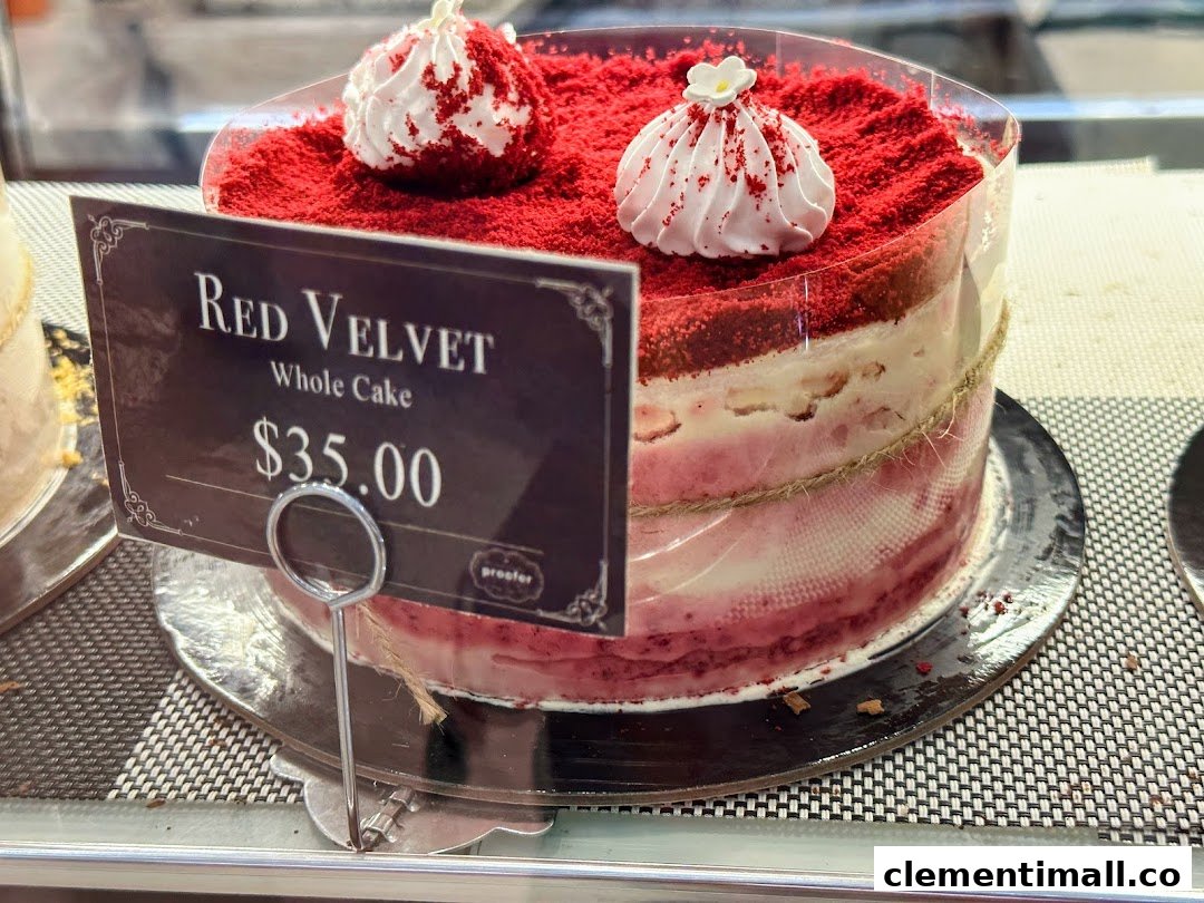 A vibrant Red Velvet whole cake with a price tag displayed in a bakery.