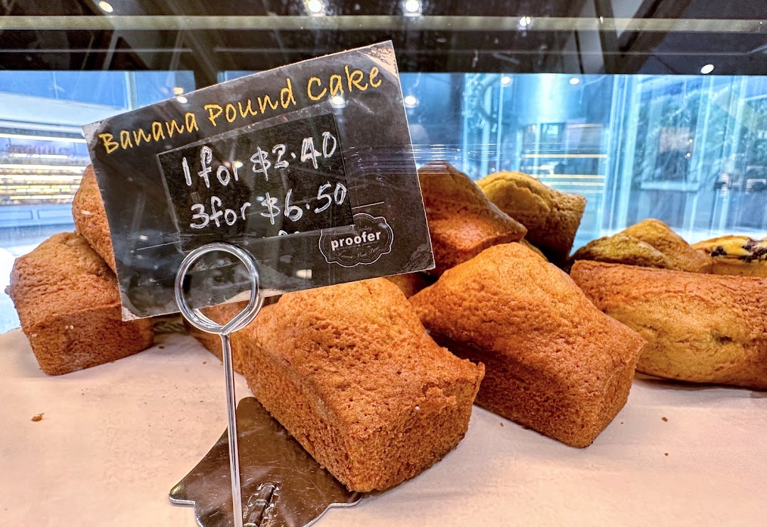A display of golden-brown banana pound cakes with a price tag at Proofer Boulangerie.