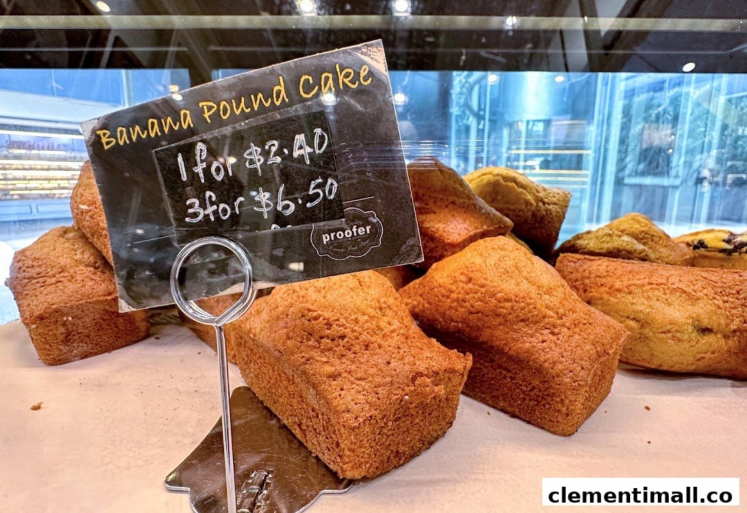 A display of golden-brown banana pound cakes with a price tag at Proofer Boulangerie.