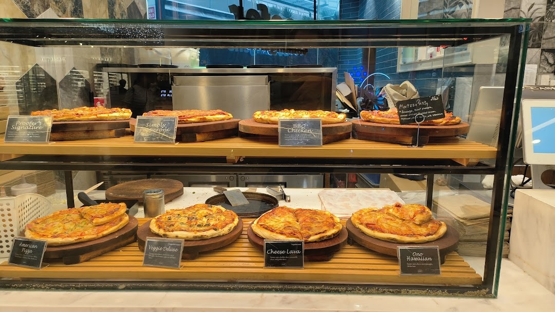 A glass display case filled with various freshly baked pizzas and flatbreads on wooden stands.