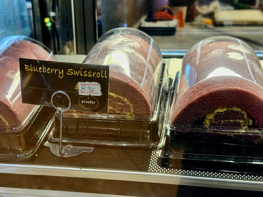Close-up of blueberry swiss rolls displayed in a bakery showcase with a price tag.