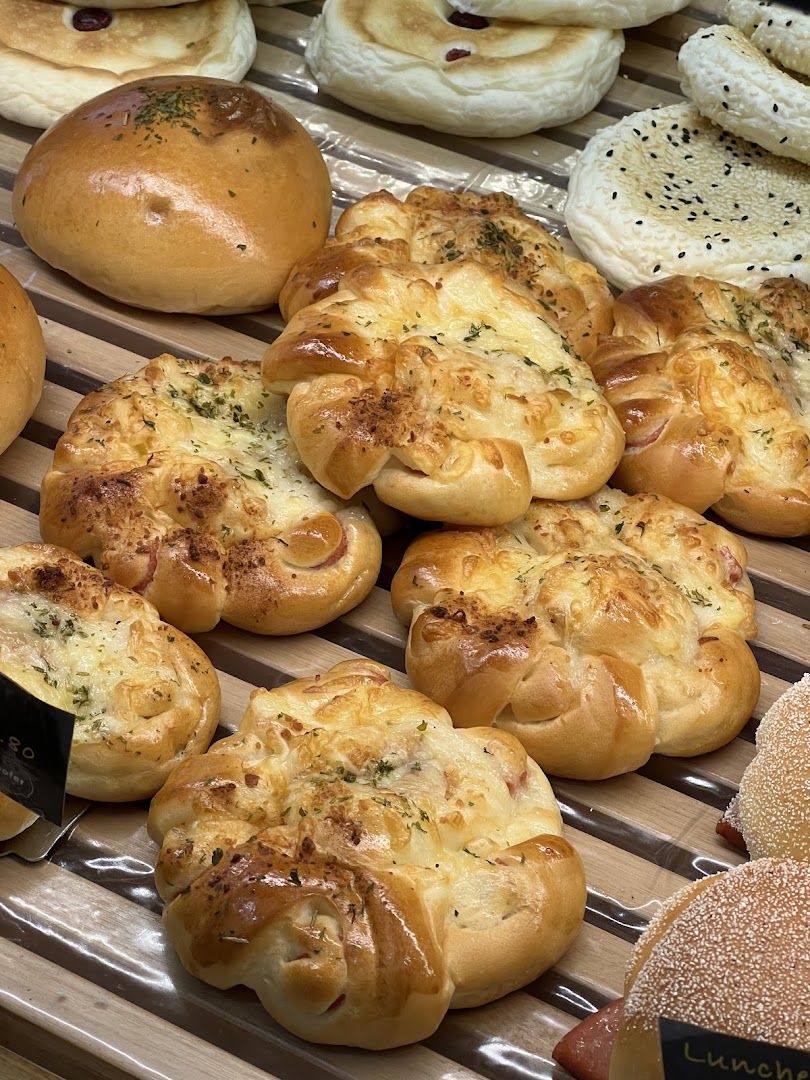 Close-up of various freshly baked breads and savory pastries displayed on wooden shelves.
