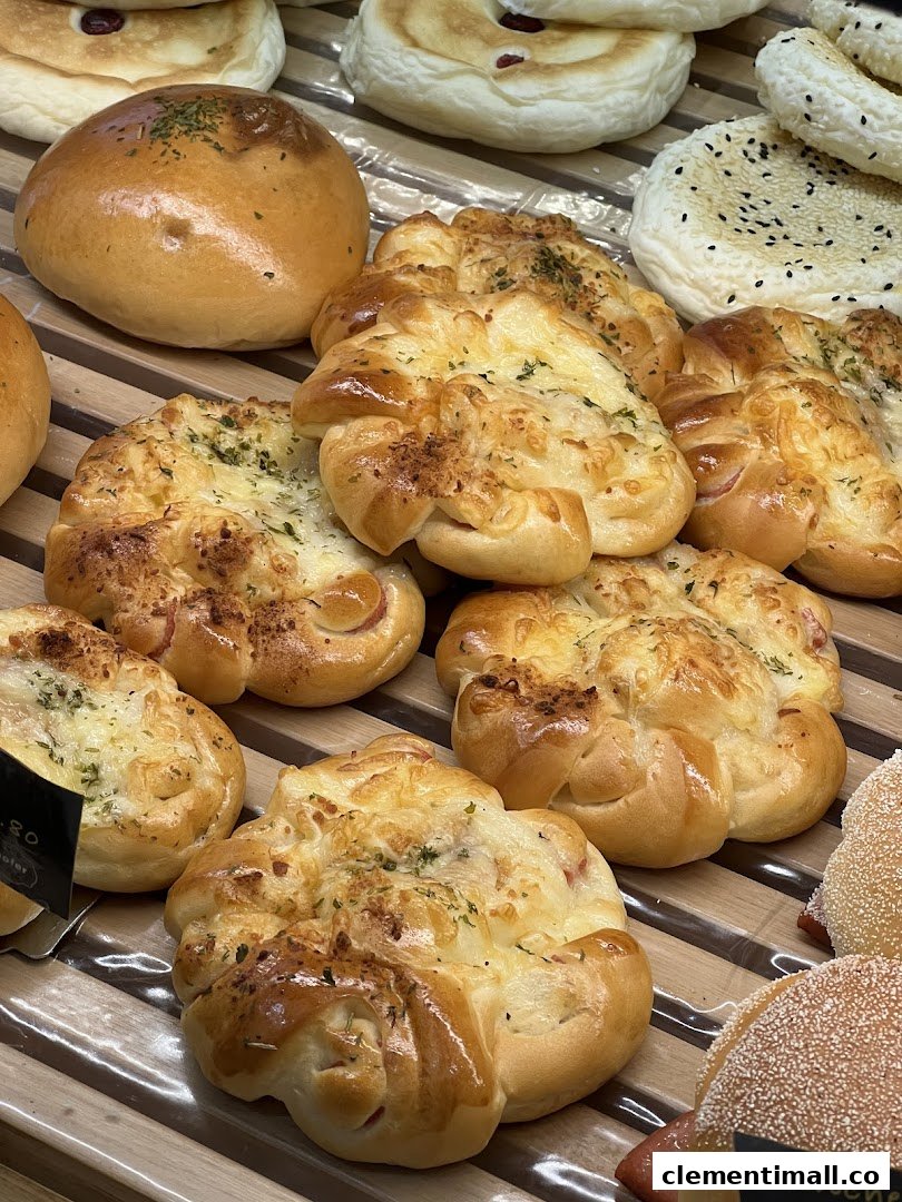 Close-up of various freshly baked breads and savory pastries displayed on wooden shelves.