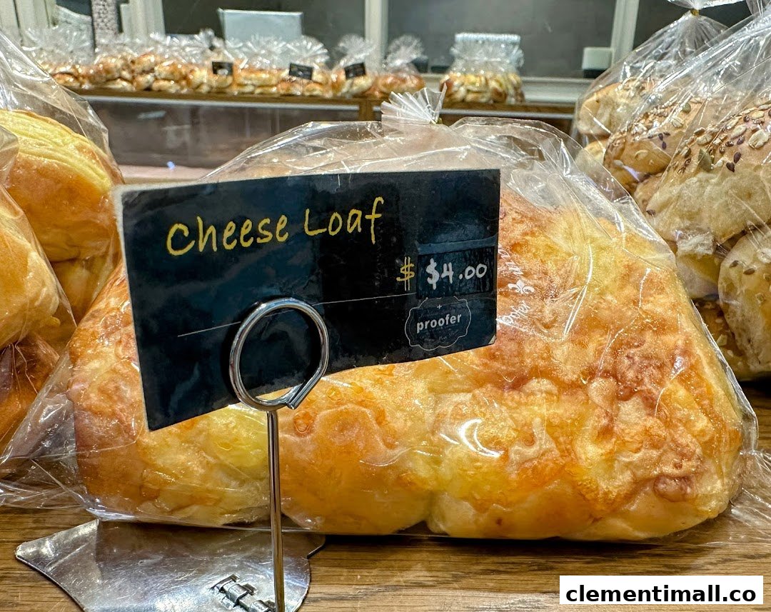A close-up of a freshly baked Cheese Loaf from Proofer Boulangerie, priced at $4.00, displayed in a clear bag.