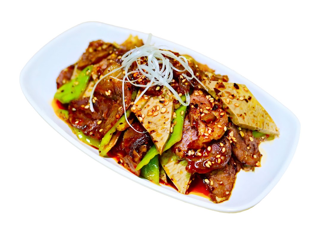 A savory dish featuring sliced meat, green peppers, and other ingredients, garnished with sesame seeds and scallions.
