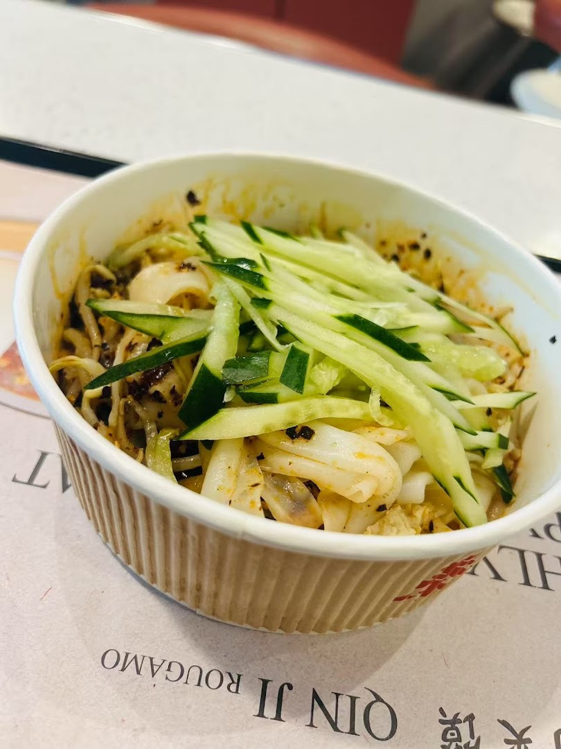 A close-up of a delicious bowl of noodles topped with fresh cucumber strips.