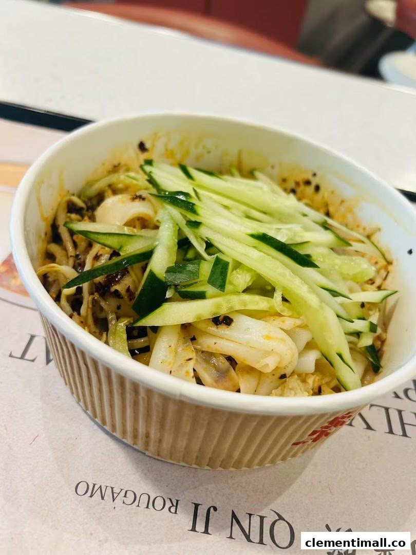 A close-up of a delicious bowl of noodles topped with fresh cucumber strips.